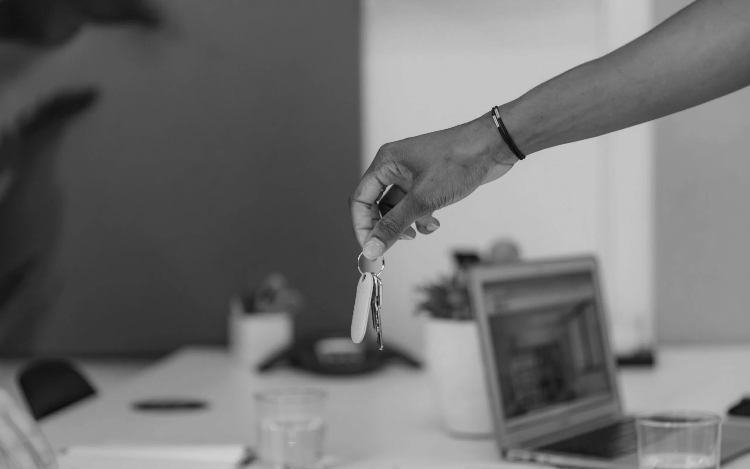 A hand offering house keys across a desk